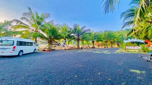 A parking area with a white van, palm trees, and a sign with Thai script. - Chanpailin Omarzaa (Krabi)