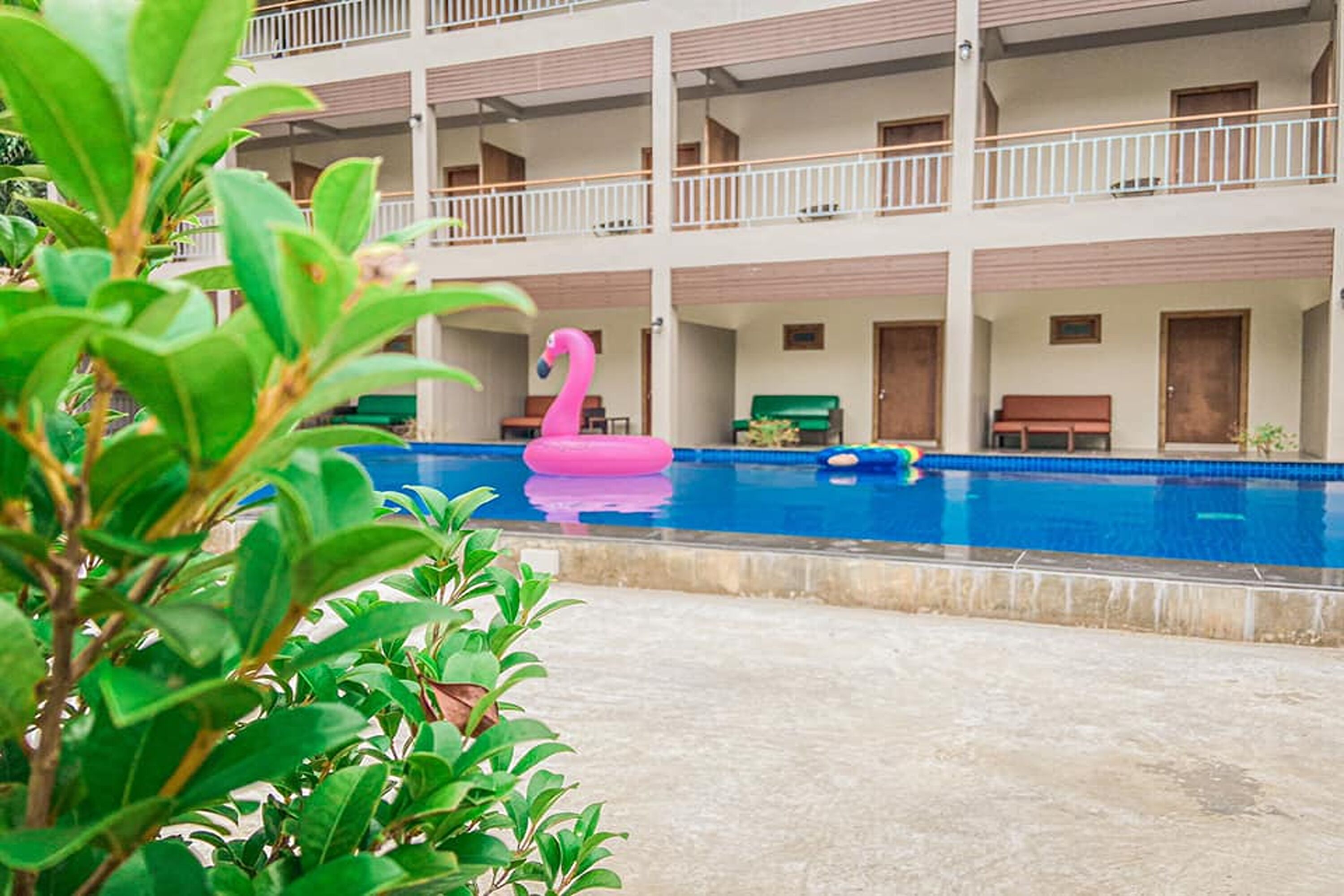 Un hotel con piscina, un flotador de flamenco rosa y un edificio de varios pisos con balcones.