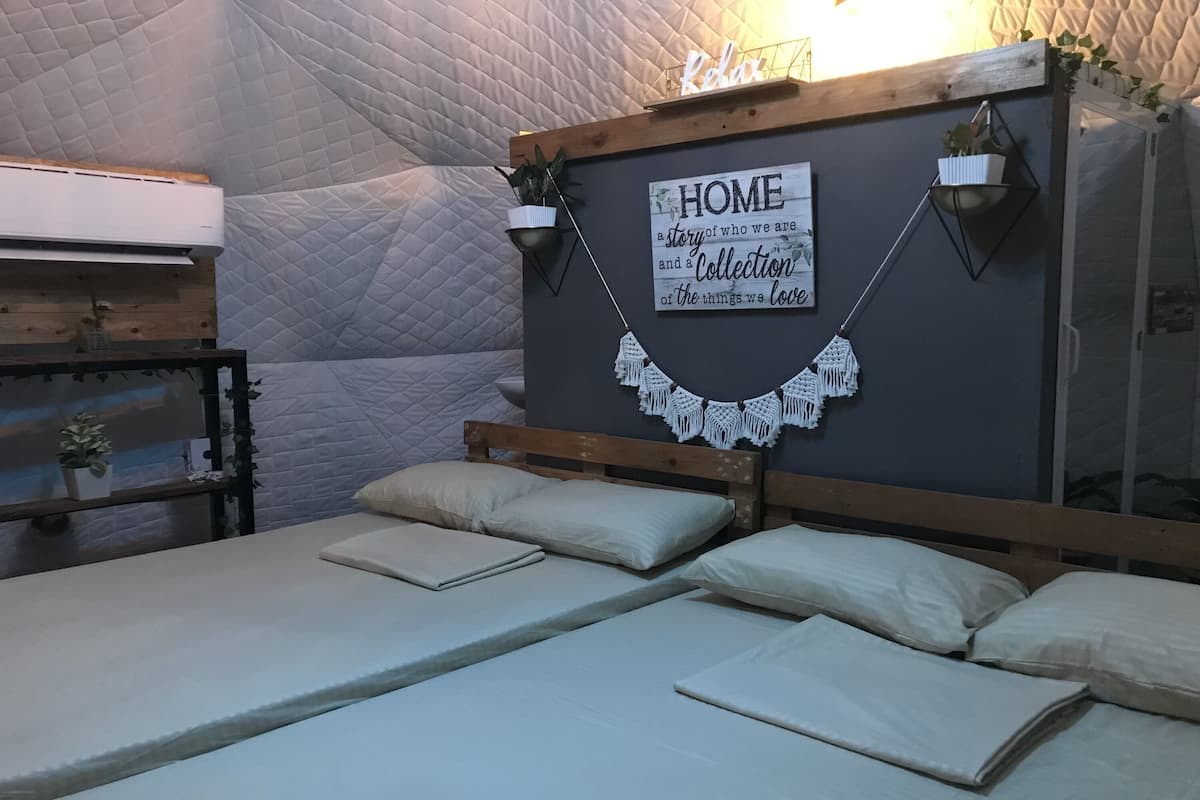 Une chambre confortable avec un lit, une table de chevet, un climatiseur fixé au mur et un panneau décoratif.