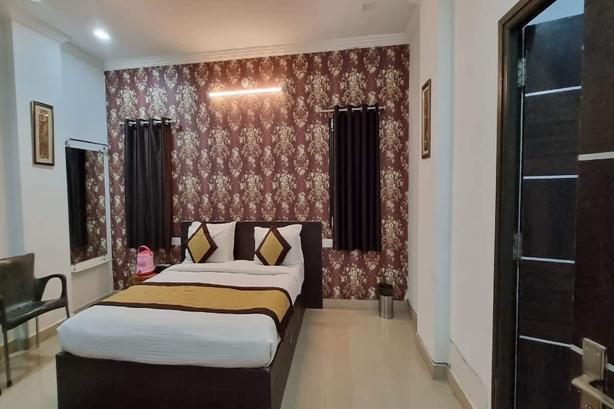 A bedroom with a large bed, curtains, a headboard, a bedside table, and a chair.