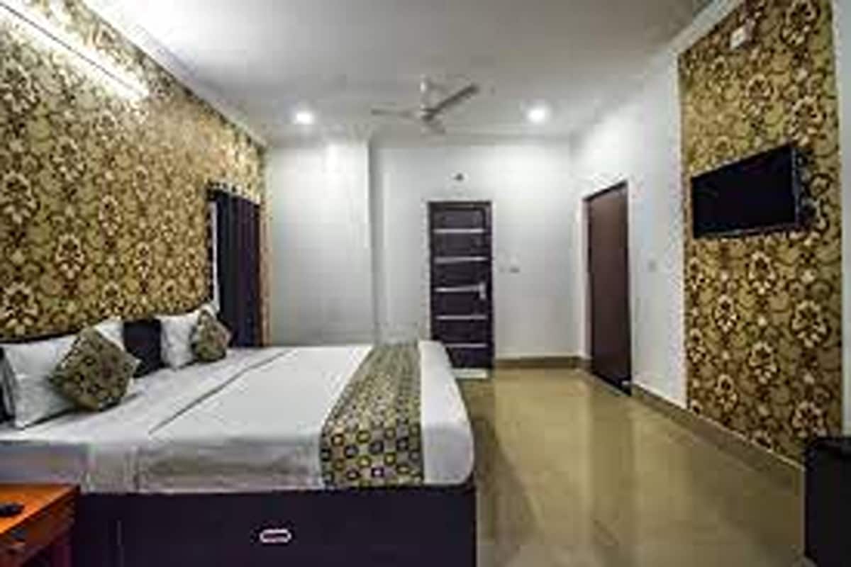 A bedroom with a bed, a wardrobe, a television mounted on the wall, and a patterned wallpaper.