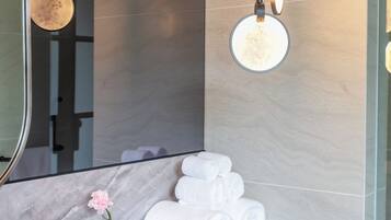A modern bathroom with a marble countertop, a round sink, and a large mirror.