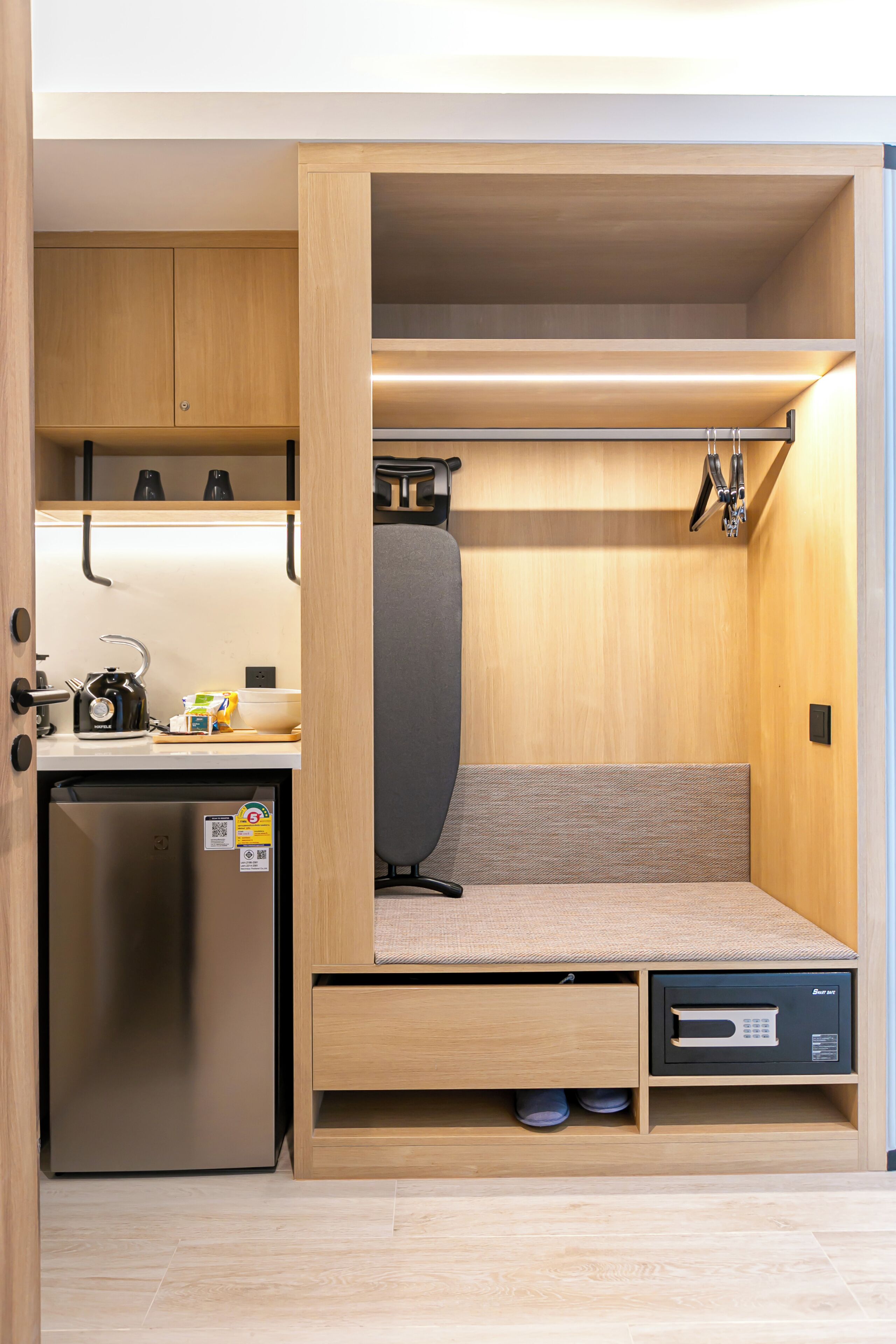 Una kitchenette compacta con refrigerador, microondas y hervidor.