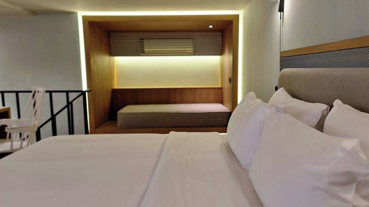 A hotel room with a bed, a small seating area, and a desk.