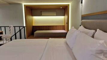 A hotel room with a bed, a small seating area, and a desk.