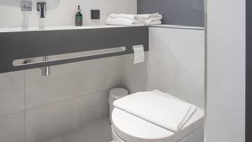 Een moderne badkamer met toilet, wastafel met spiegel en handdoekrek.