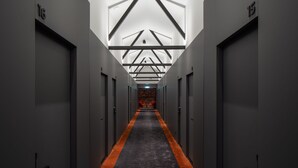 A hallway with a central carpeted path, grey walls, and doors marked with numbers. - Dunten Hotel (Tallinn)