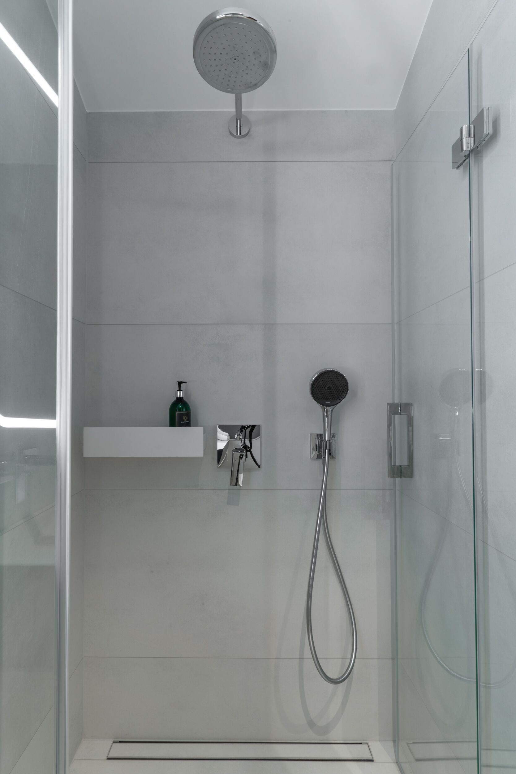 A modern shower with a handheld showerhead and a wall-mounted faucet.