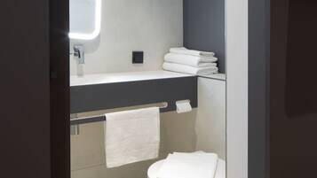 Ein modernes Badezimmer mit Toilette, Waschbecken und Spiegel.