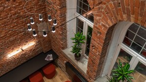 A spacious room with a brick wall, a modern chandelier, and red seating. - Dunten Hotel (Tallinn)