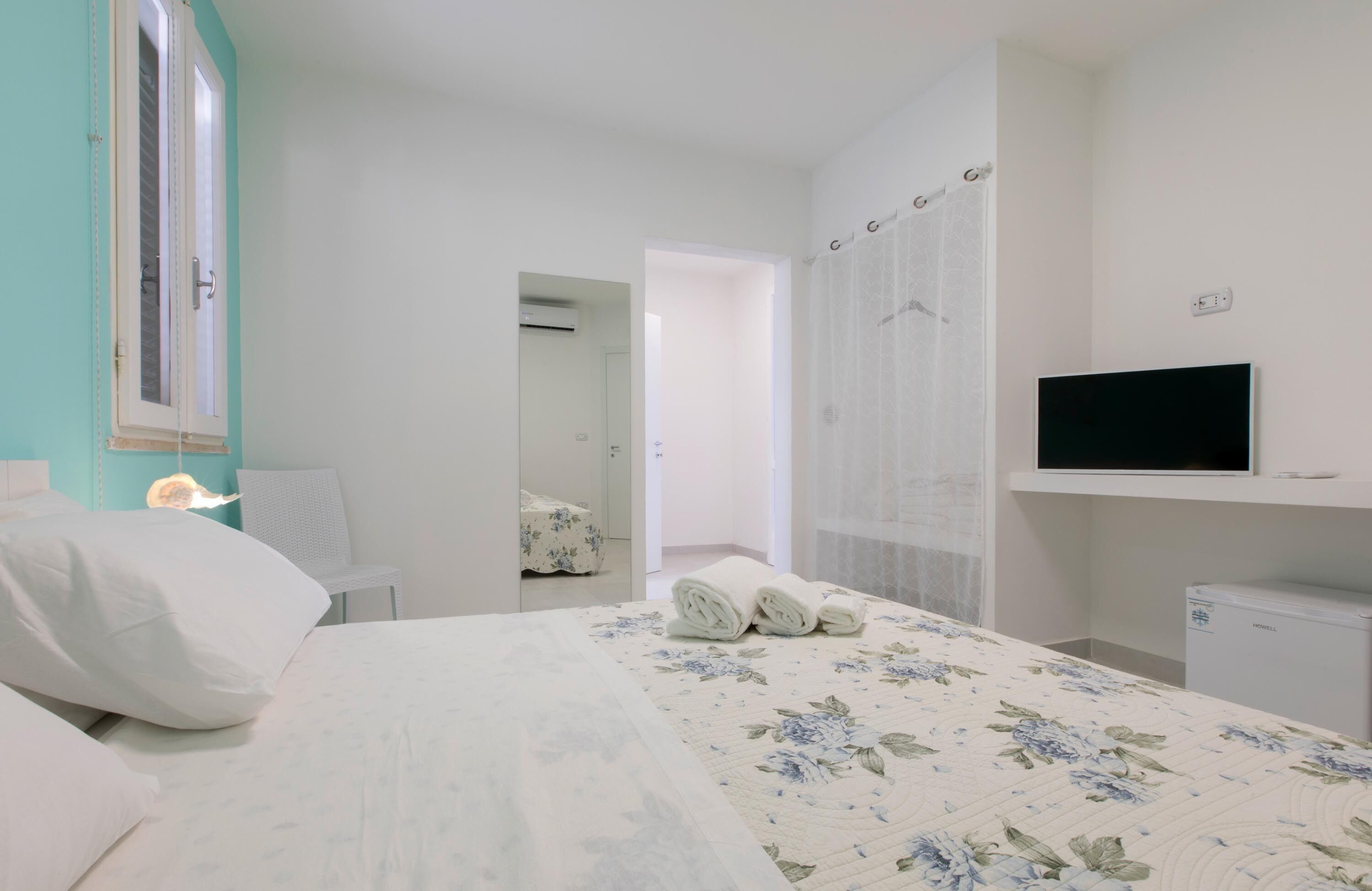 A bedroom with a bed, a TV, a desk, and a chair.