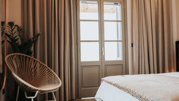 A bedroom with a bed, a chair, curtains, and a door.