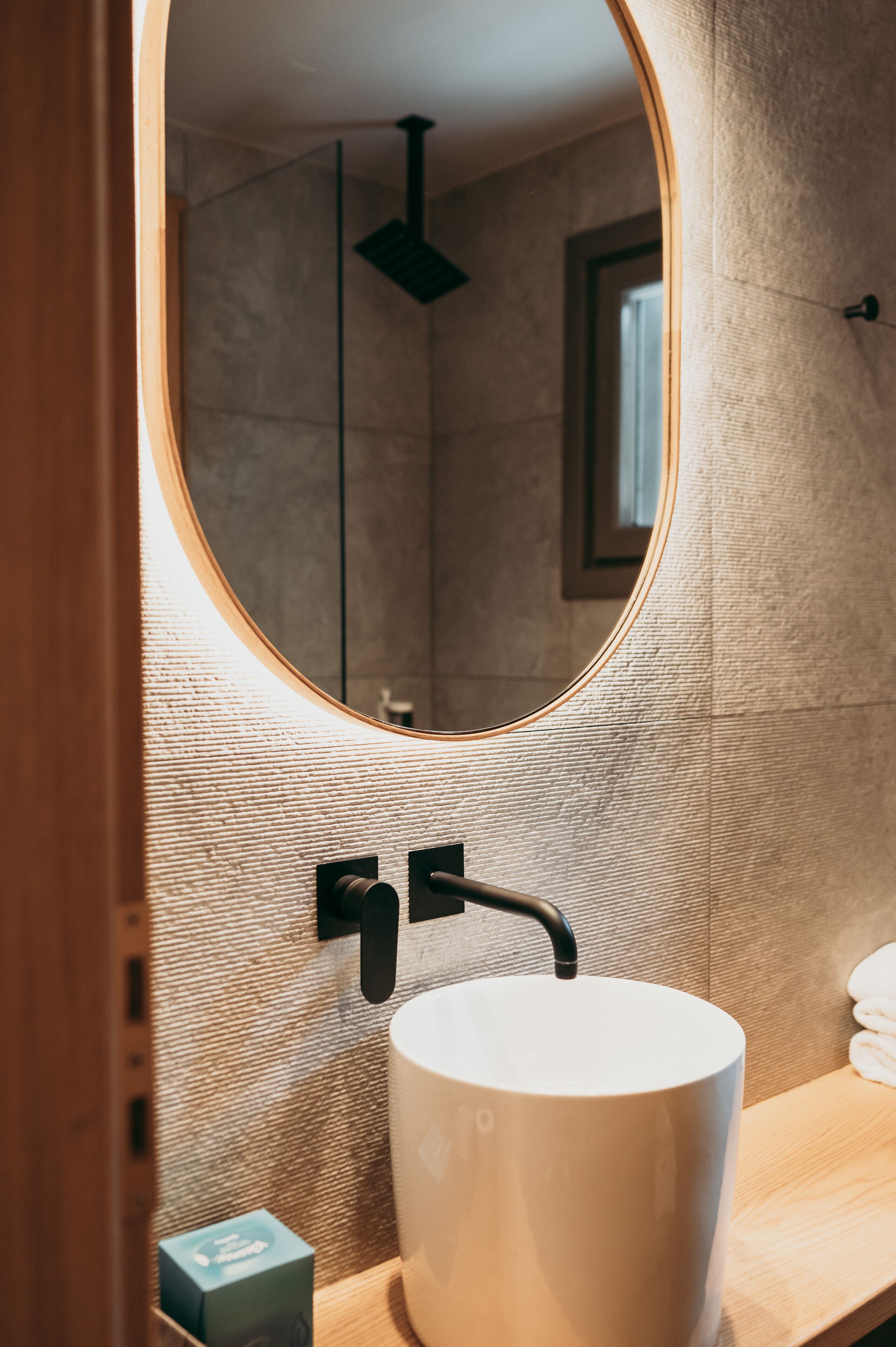 A bathroom with a round mirror, a white sink, and a towel rack.