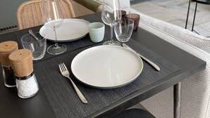 A dining table set with plates, glasses, and cutlery in a modern kitchen with grey cabinets and a herringbone backsplash. - New vacation cottage in the idyllic Ilz valley. 5 minutes to Passau (Salzweg)
