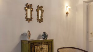 Ein Zimmer mit zwei Polstersesseln, einem Holzschrank und einer Wandleuchte.