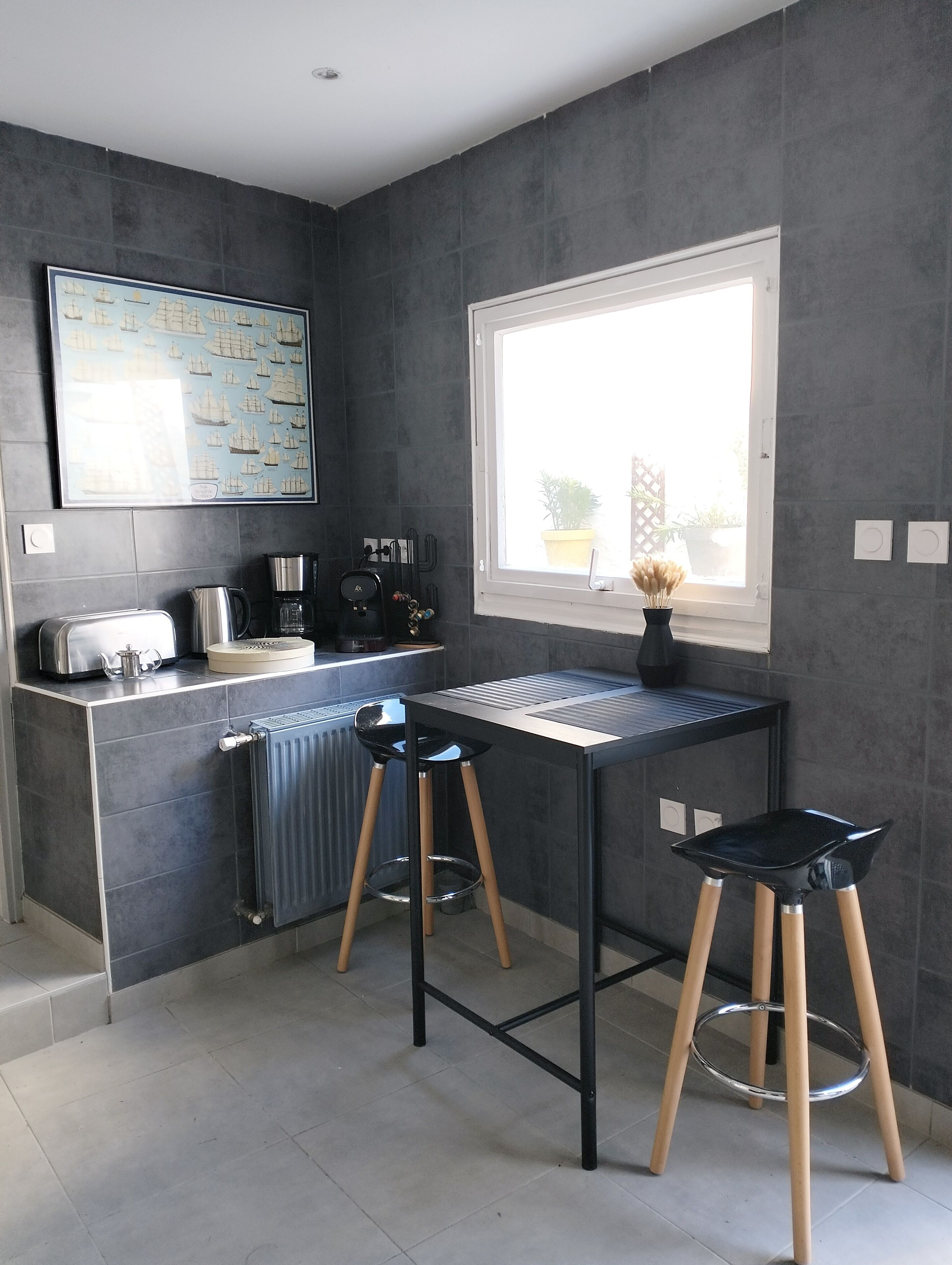 A modern kitchen with a built-in island, a large window, and a framed map on the wall.