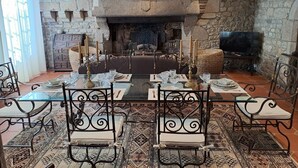 A dining area with a stone fireplace, a television, and a table set for four. - Authentic 16th-century Breton house in the heart of downtown, 2 minutes from the beach (Saint-Pol-de-Léon)