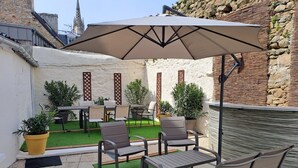 An outdoor patio with seating, a table, and a large umbrella. - Authentic 16th-century Breton house in the heart of downtown, 2 minutes from the beach (Saint-Pol-de-Léon)