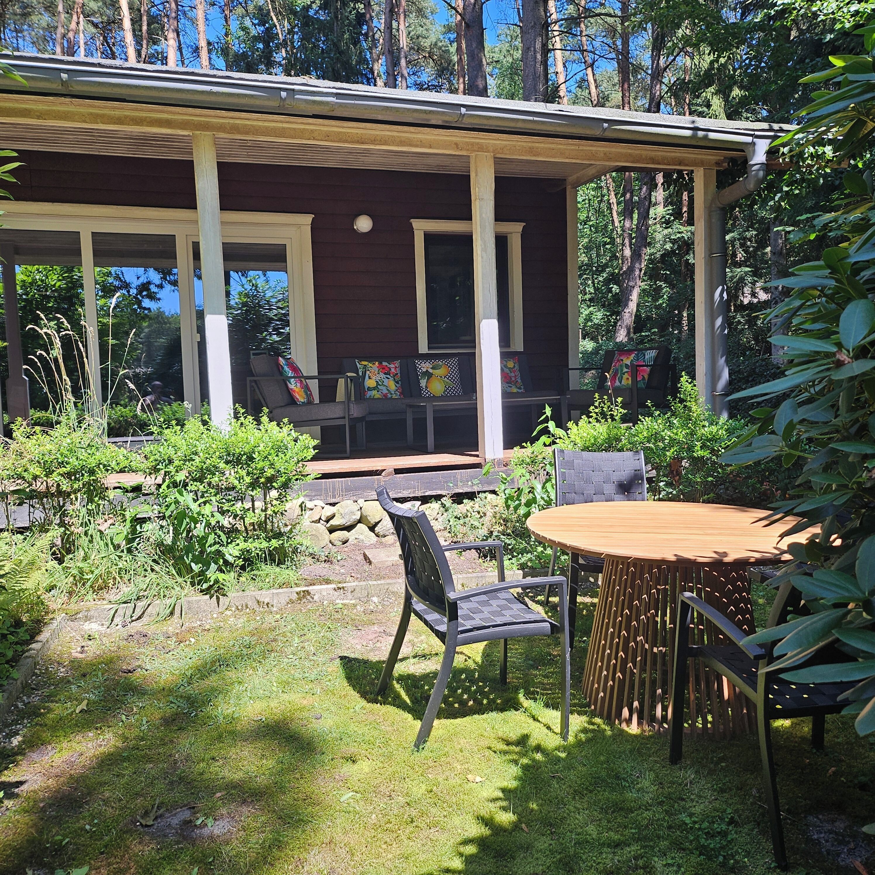 Et hus med overdækket veranda, udendørs siddepladser og en have.