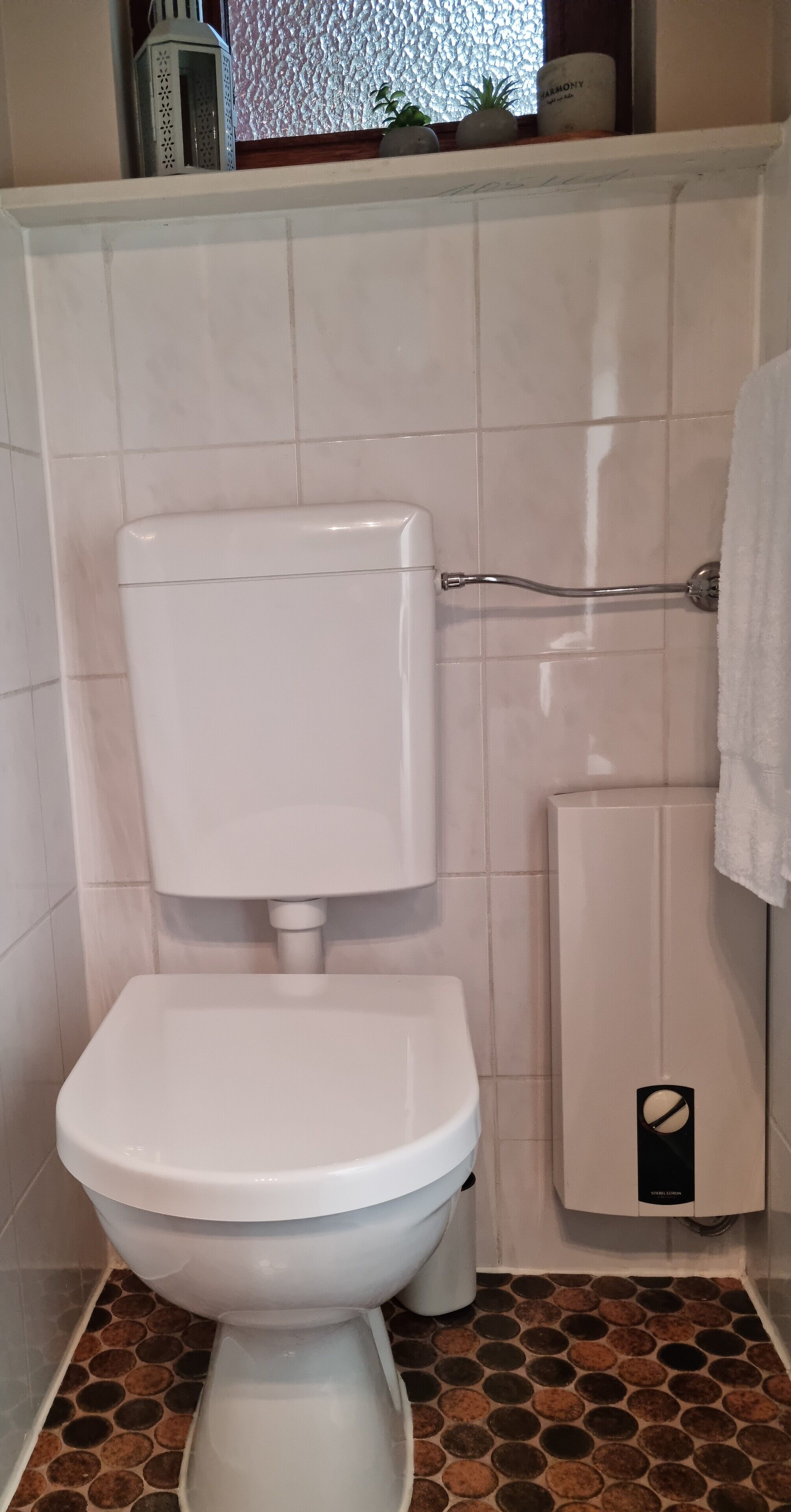 Un baño con inodoro, bidé y piso de baldosas.