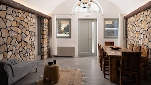 Comedor con pared de piedra, muebles de madera y vista a través de una puerta.