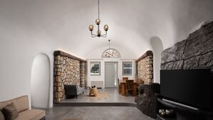 Amplia sala de estar con pared de piedra, chimenea y televisor.