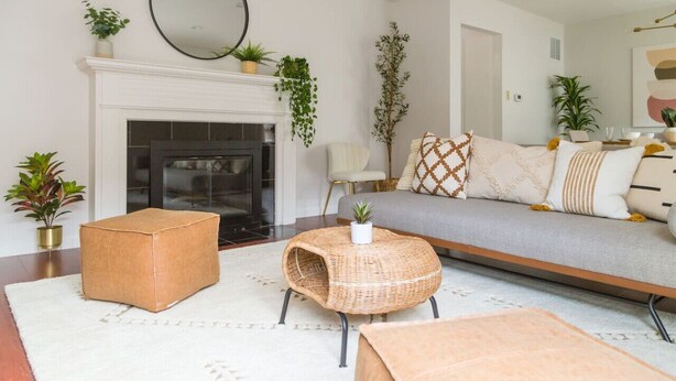 A living room with a fireplace, a sofa, a coffee table, and several potted plants. - The Laurel Pad -12-Min From SFO, Tastefully Designed, Work Station (San Mateo)