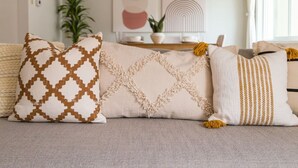 A sofa with three decorative pillows featuring geometric patterns and tassels. - The Laurel Pad -12-Min From SFO, Tastefully Designed, Work Station (San Mateo)