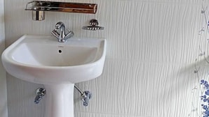 A bathroom with a white sink, a mirror, and a towel rack. - Magvaris Comfort Inn (Shillong)
