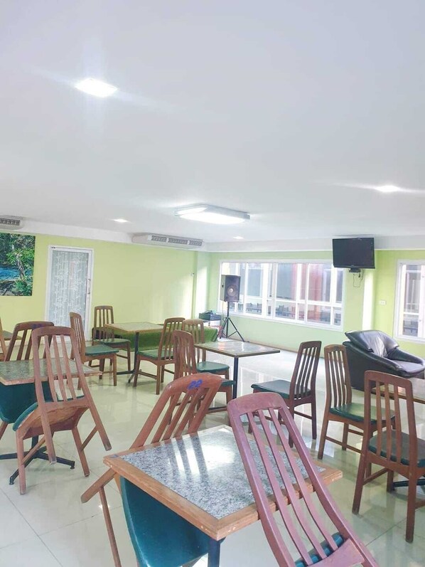 A dining area with wooden tables and chairs, a speaker, and a television on the wall.