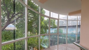 A spacious indoor area with large windows offering views of greenery and a building exterior. - MRT Thaphra spthaphra (Bangkok)