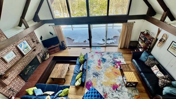 Une pièce de style loft dotée d’une grande verrière, d’une cheminée, d’un canapé, d ’une table basse et d’une bibliothèque.