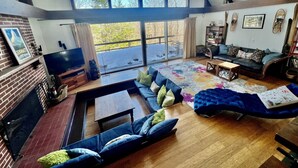 Un salon spacieux doté d’une grande fenêtre, d’une cheminée et d’un coin salon confortable.