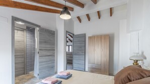 Une chambre à coucher comprenant un lit, une armoire, une table de chevet et un luminaire suspendu.