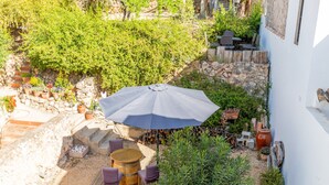 Une terrasse avec une table et des chaises, un parasol et des plantes en pot.