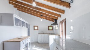 Une cuisine moderne avec des poutres en bois, un îlot central et des meubles de rangement intégrés.
