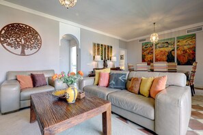 Un salon comprenant un canapé, une table basse et une œuvre d’art décorative représentant un arbre, accrochée au mur.