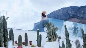 A person standing on a balcony with a view of cacti and mountains. - Lugu Lake Jimei Du Nuo Wu Yun Inn (Ninglang)
