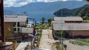 A traditional building with a tiled roof, a clear view of a mountainous landscape, and a body of water in the distance. - Lugu Lake Jimei Du Nuo Wu Yun Inn (Ninglang)