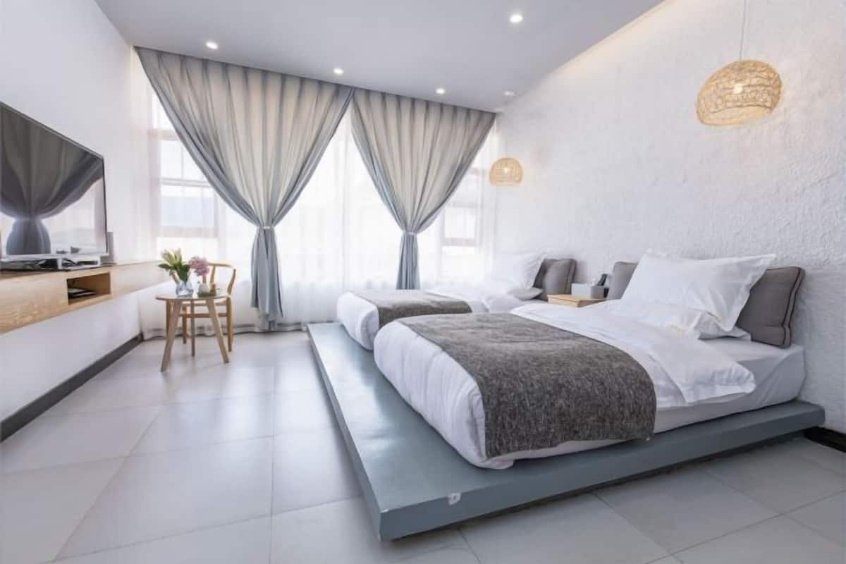 A modern bedroom with two beds, a desk, and a chair.
