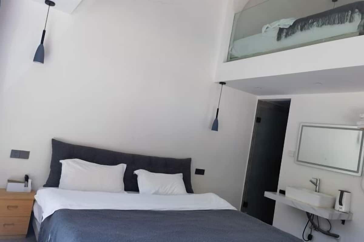 A modern bedroom with a bed, bedside tables, a mirror, and a painting on the wall.