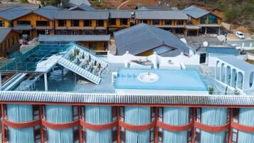Un hotel con piscina en la azotea, varios balcones y un edificio grande con techo inclinado.