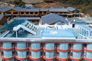 Un hotel con piscina en la azotea, varios balcones y un edificio grande con techo inclinado.