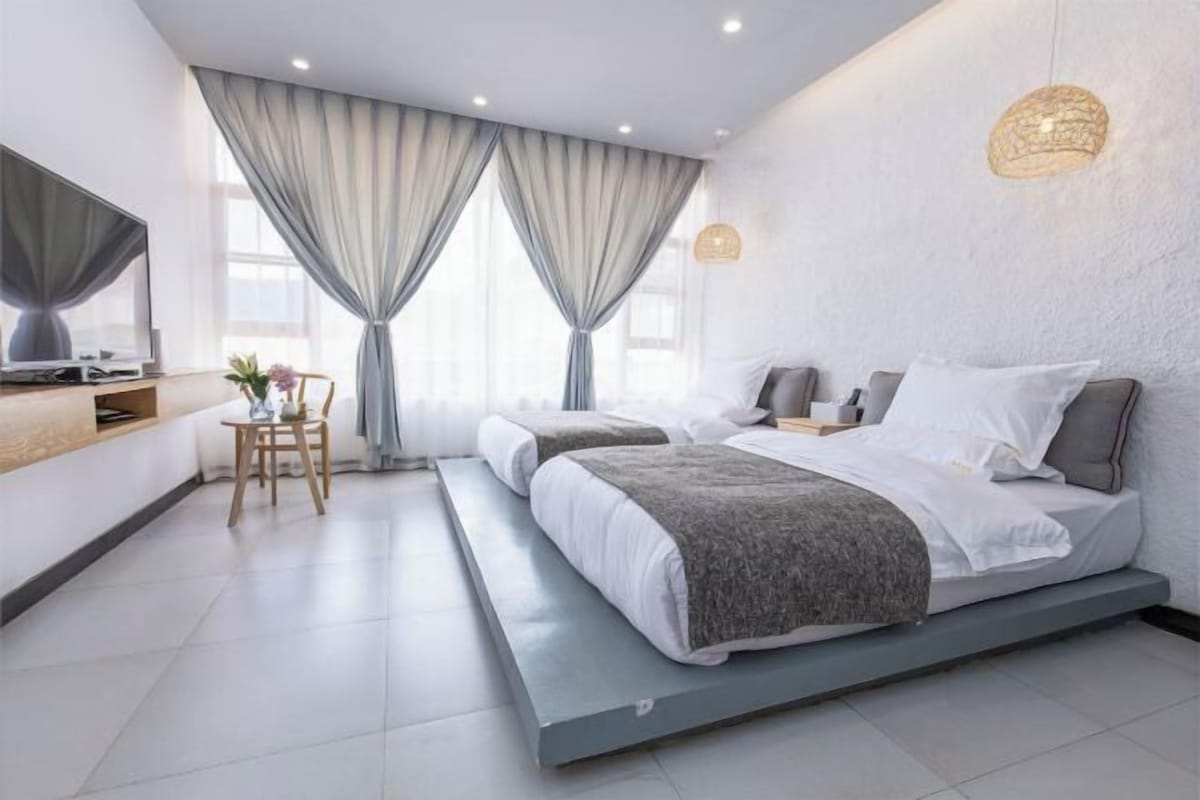Un dormitorio moderno con cama, mesitas de noche, un escritorio y una silla.