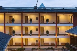 Un immeuble à plusieurs étages doté de balcons, de plantes en pot et d’un espace extérieur aménagé avec des sièges.