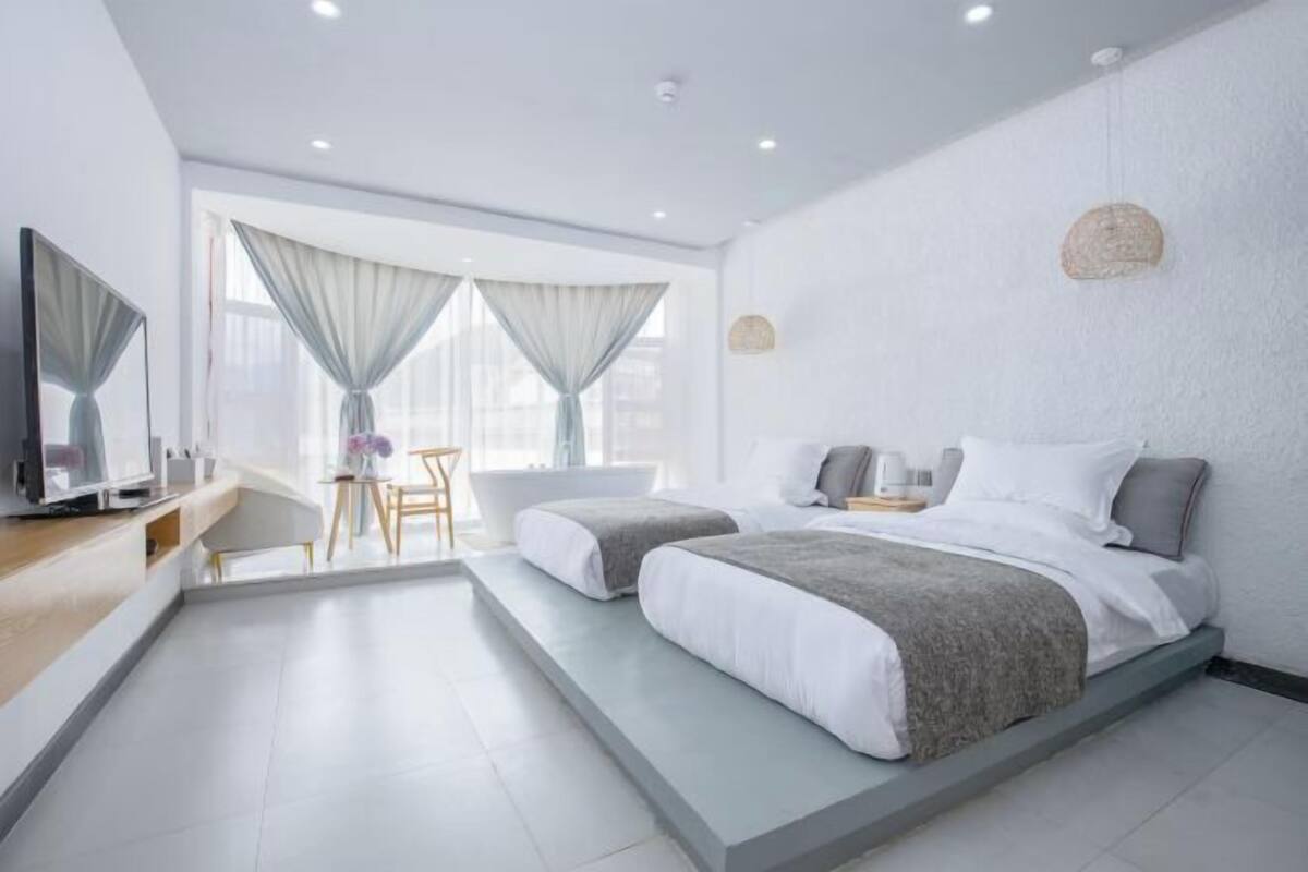 A modern hotel room with a large bed, a desk, and a view of the city.