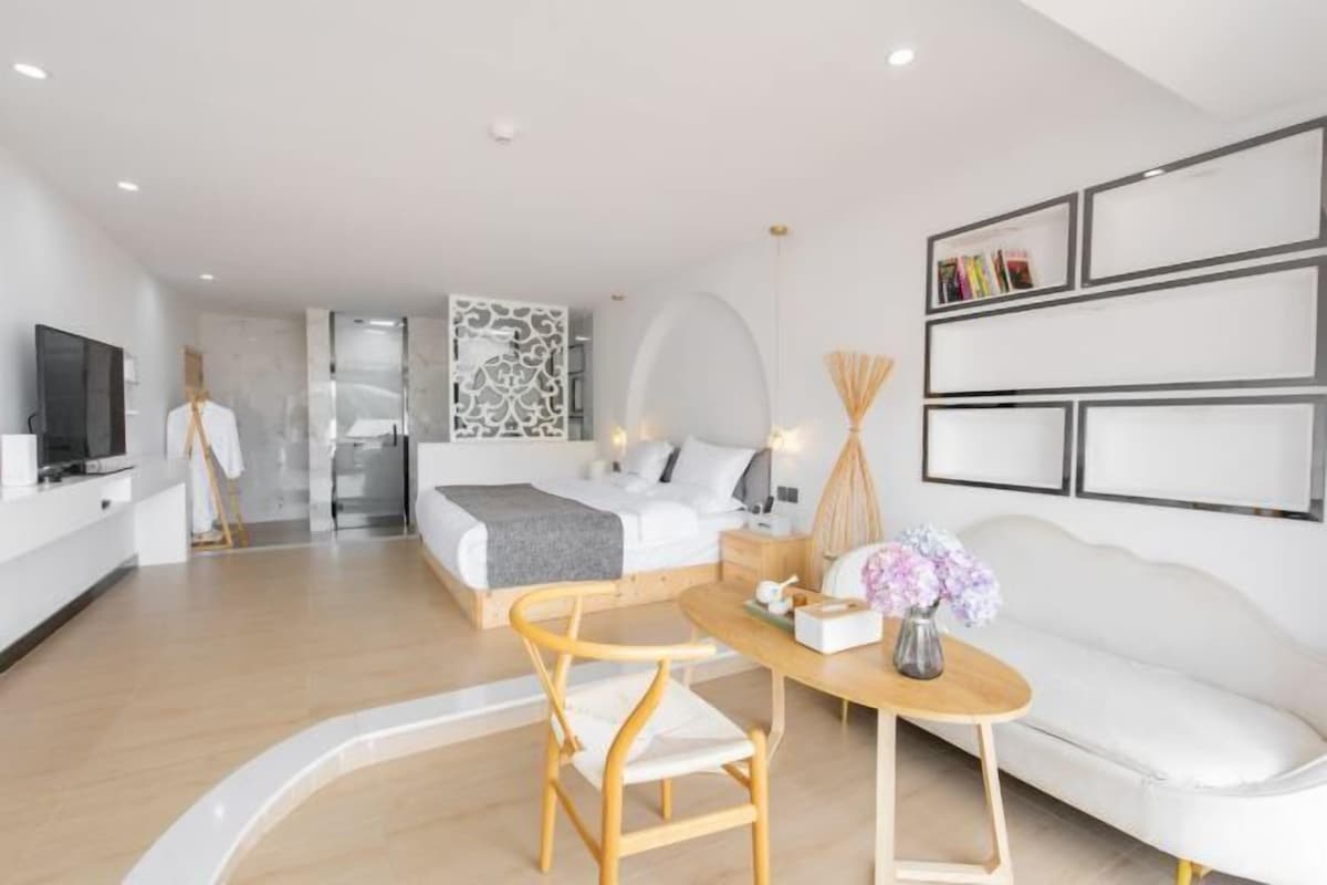 Una habitación de hotel moderna con cama, escritorio, silla, televisor y sofá.
