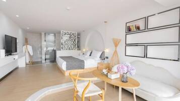 Una habitación de hotel moderna con cama, escritorio, silla, televisor y sofá.