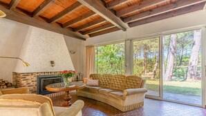 A cozy living room with a fireplace, a sofa, a coffee table, and a view of the outdoors.