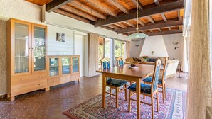 A spacious dining area with a wooden table and chairs, a large cabinet with glass doors, and a patterned rug on the floor.